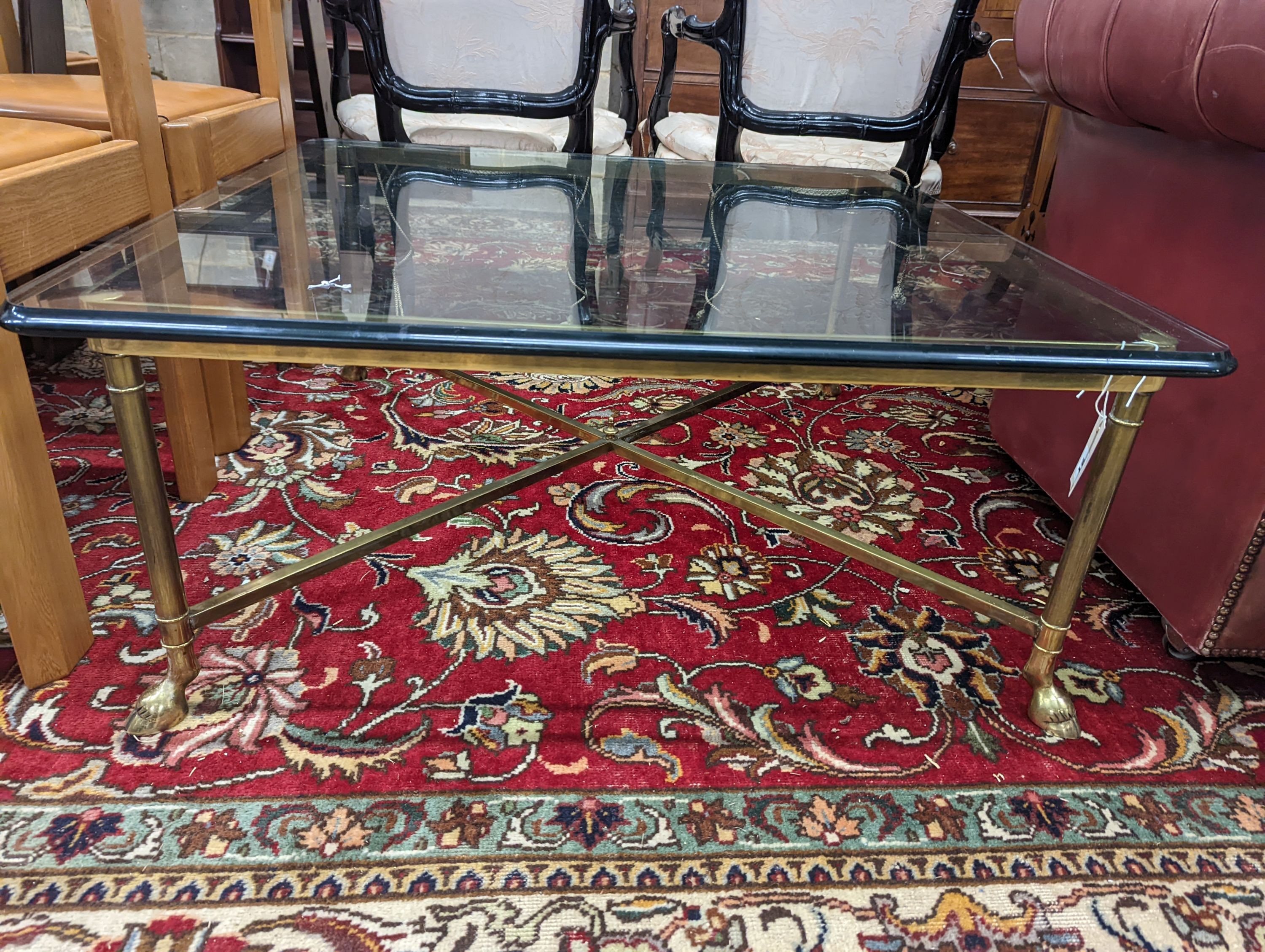 A Maison Jansen style square glass top brass coffee table on hoof feet, width 95cm, height 40cm